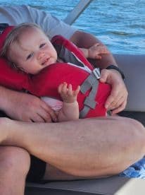 A joyful child in a life jacket enjoys a day on the boat, highlighting family fun and safety on the water.