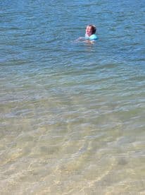 A child enjoys a fun day swimming in clear waters, showcasing the joy of summer adventures by the beach.