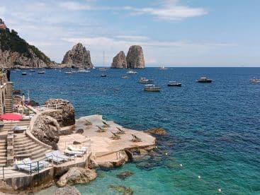 A stunning view of the coastline with boats anchored in the crystal-clear waters, showcasing the beauty of the island and perfect for a relaxing day by the sea.