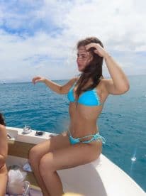 A woman enjoys the sun on a boat, capturing the essence of a fun day on the water with friends. Perfect for summer adventures and beach parties.