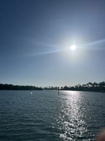 A serene view of the sun shining over calm waters, creating a beautiful reflection — a perfect backdrop for a day on the water.