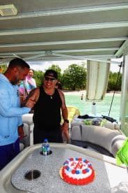 A joyful birthday celebration aboard a boat, featuring a cake and friends enjoying the moment together — perfect for memorable gatherings on the water.