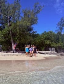 A cheerful group poses on the beach, enjoying a sunny day by the water — perfect for memorable beach outings and celebrations.