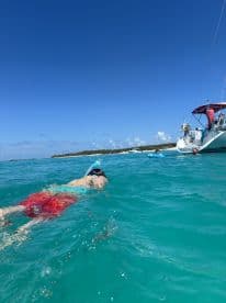 A child snorkels in vibrant turquoise waters while a boat is anchored nearby, capturing the essence of a fun-filled day on the water.