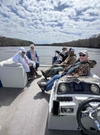 A cheerful group enjoys a relaxing day on a pontoon boat, taking in the scenic river views — perfect for gatherings with friends and family.