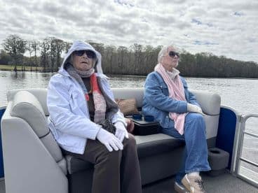 Two women enjoy a relaxing moment on a boat, surrounded by serene waters and nature — perfect for a peaceful day out on the water.