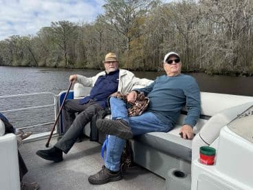 Two gentlemen relax on a pontoon boat, enjoying the serene views of the surrounding nature — a perfect setting for leisurely outings on the water.