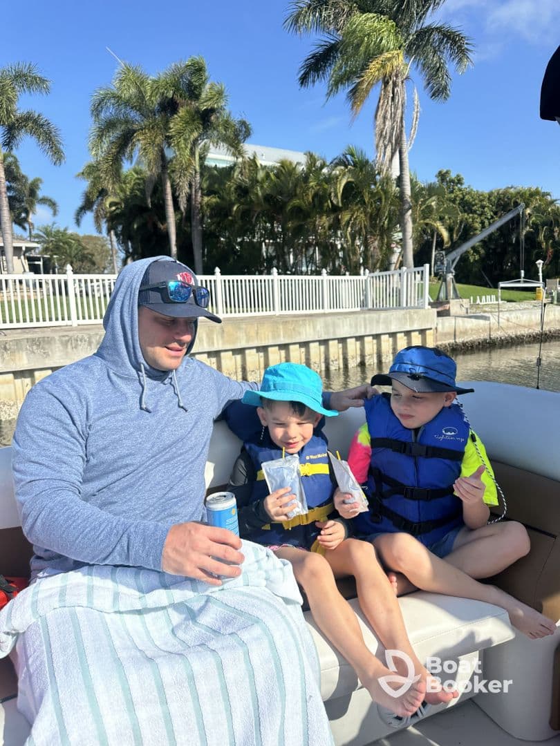 A father enjoys a relaxing moment on a boat with his two children, sharing drinks and smiles — a perfect family outing on the water.