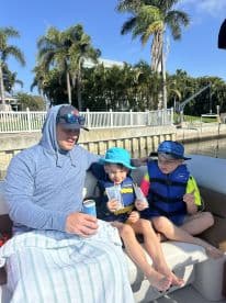 A father enjoys a relaxing moment on a boat with his two children, sharing drinks and smiles — a perfect family outing on the water.
