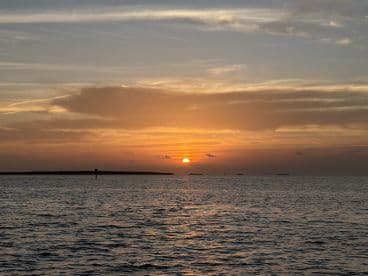 A stunning sunset over tranquil waters, with an island silhouette in the background — perfect for serene evening boat cruises.