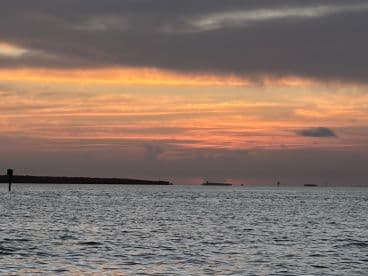A serene sunset over the water, showcasing the tranquil beauty of the coastline — perfect for evening boat cruises.