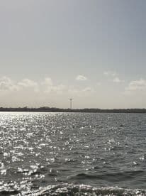 A distant view of a cross on the horizon over shimmering water, creating an ambiguous scene that lacks clarity.