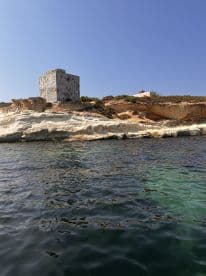 A picturesque view of a historic tower perched on a rocky coastline, showcasing the beauty of the surrounding waters — an ideal spot for sightseeing and exploration.