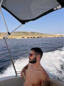 A man enjoys a sunny day on a boat, taking in the beautiful sea views — perfect for a relaxing getaway on the water.