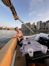 A woman relaxes on the lounge of a boat, enjoying the serene waterfront view — perfect for leisure and relaxation on the water.