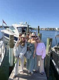 A cheerful group of friends poses on the dock in front of a stylish boat, ready for a fun day on the water. Perfect for celebrations and memorable outings.
