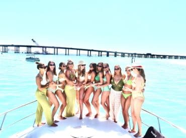 A lively group of friends celebrates together on a boat, enjoying a sunny day on the water — perfect for bachelorette parties or summer gatherings.