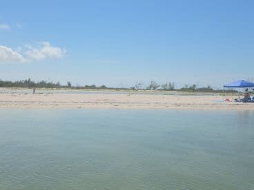 A serene beach scene featuring a person walking along the shore, perfect for showcasing tranquil island getaways and relaxation by the water.