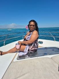 A woman enjoys a sunny day on the boat, sipping a drink and soaking in the beautiful waters — perfect for a relaxing getaway.