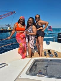 A joyful group of friends poses on the deck of a boat, celebrating their time on the water under a clear blue sky — perfect for summer outings and memorable adventures.