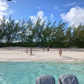 A lively group enjoys a day at the beach, playing and swimming in the clear waters — a perfect sandbar stop for fun and relaxation.