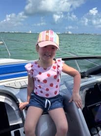 A cheerful child enjoys a sunny day on a boat, showcasing the fun and adventure of family outings on the water.