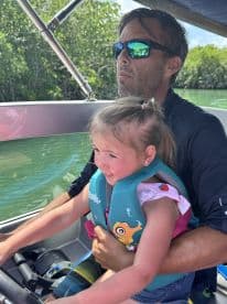 A joyful moment as a child steers the boat with guidance from an adult, showcasing a fun family boating experience.