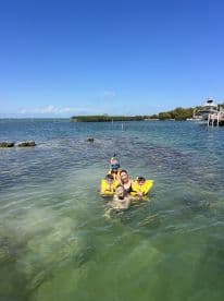 A joyful family enjoys snorkeling in clear waters, showcasing a fun-filled day of swimming and exploration in a tropical paradise.
