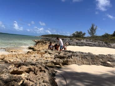 A family explores the rocky shore at a beautiful beach, enjoying a day of adventure and discovery in a tropical paradise.
