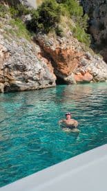 A swimmer enjoys the crystal-clear waters near a rocky cave, showcasing the beauty of a secluded swimming spot — perfect for adventure seekers.