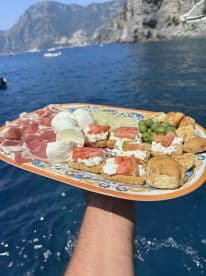 A delicious charcuterie platter featuring a variety of snacks, perfect for enjoying on a boat trip amidst stunning coastal views.