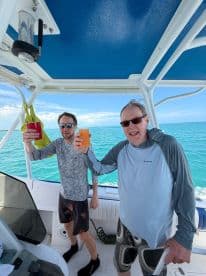 Two friends celebrate on a boat with colorful cocktails, enjoying a perfect day on the water — ideal for group outings and fun adventures.