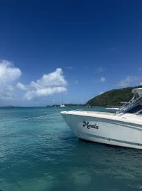 A stunning view of the 'Manta' boat docked in crystal-clear waters, surrounded by a picturesque landscape and vibrant blue skies.