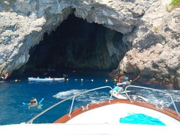 A vibrant scene of adventure as guests enjoy snorkeling and kayaking near a stunning cave entrance, showcasing the excitement of exploring underwater wonders.