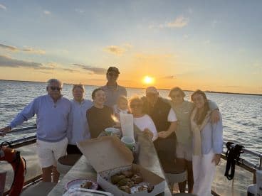 A joyful family gathers on a boat at sunset, celebrating together with snacks and drinks — a perfect moment for cherished memories on the water.