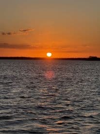 A stunning sunset over calm waters, creating a picturesque backdrop perfect for evening boat cruises.