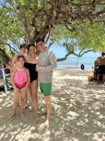 A joyful family poses together on the beach, capturing a memorable moment in a tropical paradise, perfect for family vacations and celebrations.