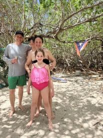 A joyful family poses together on the beach, capturing a memorable moment under the sun — perfect for family vacations and beach outings.