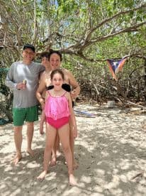 A joyful family poses together on the beach, capturing a memorable moment in a tropical paradise.