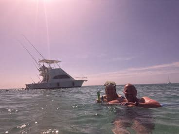 A happy couple enjoys a refreshing swim while snorkeling near their boat, creating unforgettable memories in the beautiful ocean.