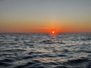 A breathtaking sunset over the ocean, casting vibrant colors across the water — a perfect backdrop for evening boat cruises.