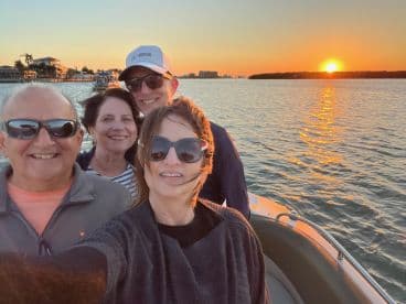 A joyful group of friends captures a sunset selfie aboard a boat, creating lasting memories on the water.