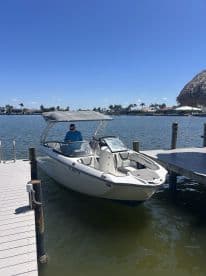 A sleek speedboat docked at a marina, with a person preparing for a day on the water under a clear blue sky.