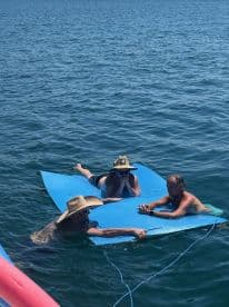 A group of friends enjoys a relaxing day on a floating mat in the water, perfect for sunbathing and socializing during their boating adventure.