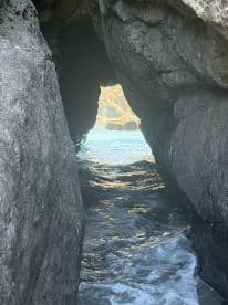 A stunning view through a rocky archway leading to tranquil waters, showcasing the natural beauty of the coastline — perfect for exploring hidden gems on a boat trip.