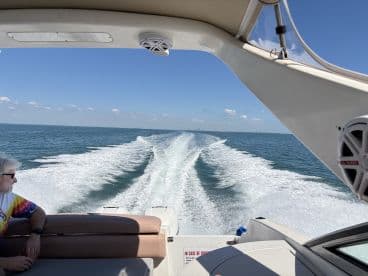 A scenic view from the helm of a boat, showcasing a passenger enjoying the ride while cruising through beautiful waters — perfect for adventure seekers and boating enthusiasts.