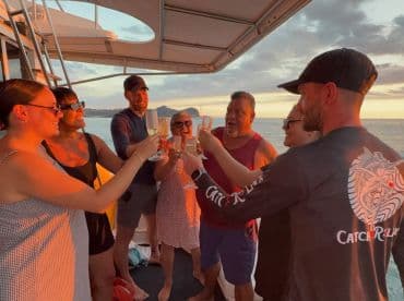 A joyful group toasts with cocktails aboard a boat during a stunning sunset, capturing the essence of celebration and camaraderie on the water.