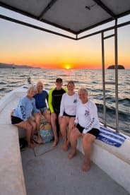 A cheerful group of friends enjoys a sunset aboard a boat, capturing a memorable moment on the water — perfect for celebrations and shared experiences.