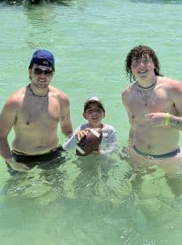 A fun moment captured with a group of friends and a child playing football in the clear waters, perfect for family outings and beach activities.