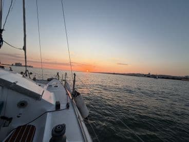 A serene view of a sailboat at sunset, capturing the tranquil beauty of the open water and the vibrant colors of the sky.
